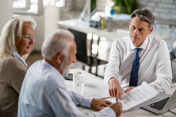 bank-manager-having-meeting-with-senior-couple-pointing-place-they-need-sign-contract_637285-1810